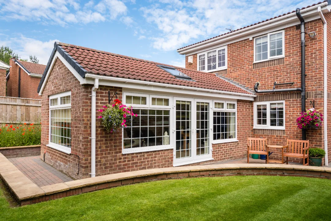 brick house extension with frame windows and french doors opening into garden